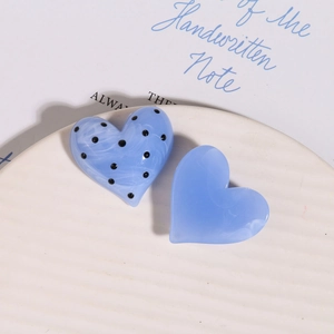 Dettaglio di ciondoli a cuore blu marmorizzati con pois neri per fermagli per capelli DIY