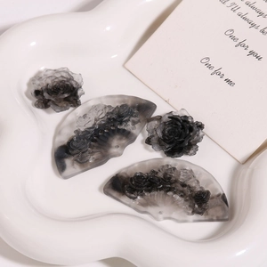 Close-up of translucent smoke grey resin fan and rose flower charms with marble texture