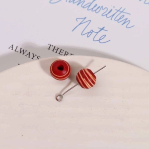 Macro detail of 10mm red and yellow striped wooden beads with silver metal eye pins