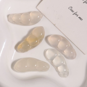 Détail macro de cinq pendentifs en agate naturelle translucide sur un plateau blanc