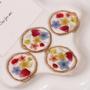 Macro shot of circular resin pendants with colorful dried flowers and gold alloy edges