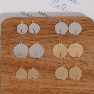 Flat round earring posts with loops in gold and silver finishes on a wooden board