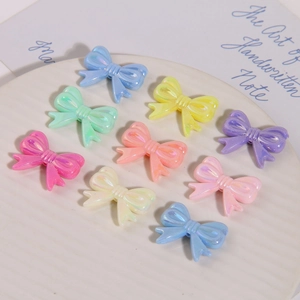 Vue macro de breloques nœuds en résine irisée pour bijoux DIY sur plateau blanc