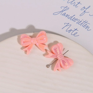 Détail de breloques nœuds en résine irisée rose avec tiges pour bijoux artisanaux