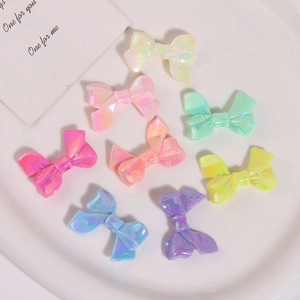 Macro shot of colorful iridescent resin bow charms in a minimalist white ceramic tray