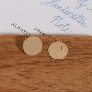 Detail of gold-plated round earring studs with loops on a wooden base for DIY jewelry making