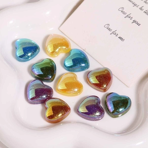 Détail macro de perles de cœur en résine colorées à paillettes sur plateau céramique