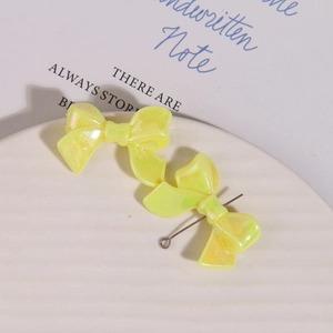 Detail of yellow iridescent bow charms with pearlescent finish in a white ceramic dish