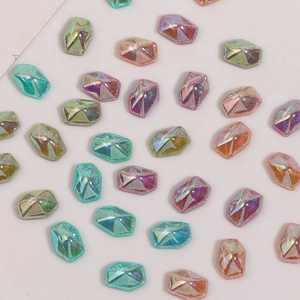 Makro-Detail von geometrischen Harz-Charms mit Glitzer in verschiedenen Pastellfarben