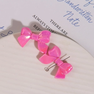 Macro view of pink pearlescent 3D bow jewelry pendants with silver metal rings