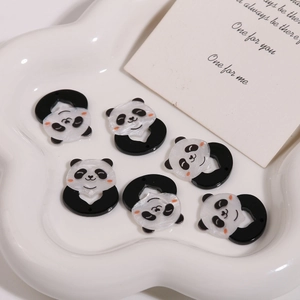 Macro view of six cartoon panda acrylic charms for DIY jewelry making on white tray