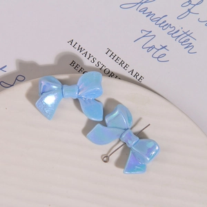 Macro detail of iridescent blue bow charms with metal link for DIY jewelry making