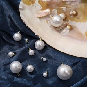 Detail of assorted white imitation pearl pendants with gold rings on blue silk