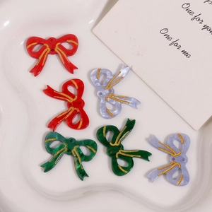 Dettaglio di ciondoli a fiocco fai-da-te con linee glitterate dorate su vassoio ceramico