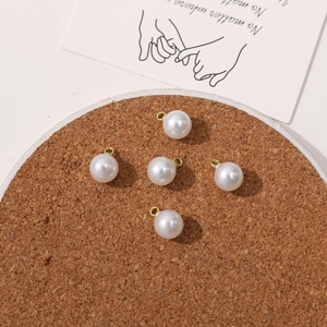 Detail of five round faux pearl charms with golden metal loops for DIY jewelry making