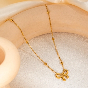 Detailed view of golden bow pendant necklace with small beads on a minimalist chain