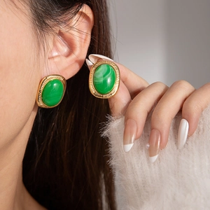 Primer plano de pendientes ovalados dorados con piedra malaquita verde en modelo