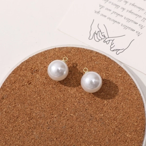 Close-up of white round faux pearl charms with gold loops for DIY jewelry making