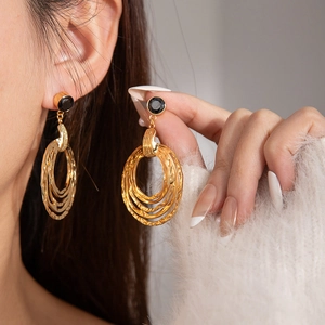 Detailed view of vintage gold multi-layered hammered hoop earrings with black circular studs