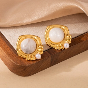 Primer plano de pendientes vintage dorados con piedra de mármol y pequeñas perlas laterales