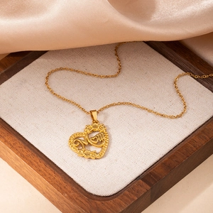 Détail d'un collier coeur doré avec lettrage MOM sur fond de soie couleur champagne