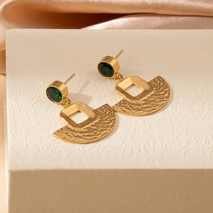 Close-up of vintage gold fan-shaped stud earrings with green gemstones on silk