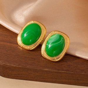 Primer plano de pendientes vintage dorados con piedra de mármol verde sobre seda