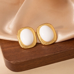 Primer plano de pendientes vintage dorados con piedra de ámbar y perla blanca