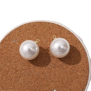 Creamy white round imitation pearl pendants with gold metal loops on cork base
