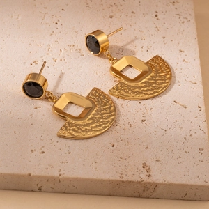 Detail of vintage square fan earrings with black gemstone and gold hammered texture finish