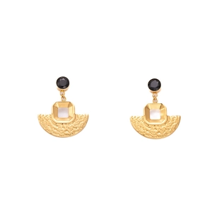 Macro shot of retro geometric earrings featuring hammered gold finish and black circular inlay