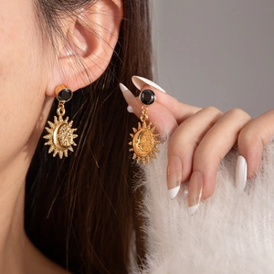 Detail van vintage gouden zon en maan oorbellen met zwarte edelstenen op een model