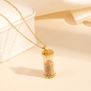 Detail of gold-plated stainless steel necklace with transparent cylinder pendant and gold foil