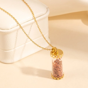 Close-up of golden cylinder glass pendant filled with brown stones on white leather box