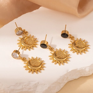 Detail van vintage zon en maan oorbellen met zwarte en heldere stenen op witte steen