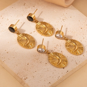 Detailopname van gouden zon- en maan oorbellen met zwarte en heldere kristallen studs