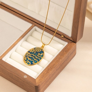 Macro detail of oval pendant with blue enamel wave pattern in a velvet jewelry box