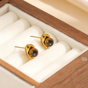 Macro shot of vintage gold earrings with brown tiger eye stones in a wooden jewelry box