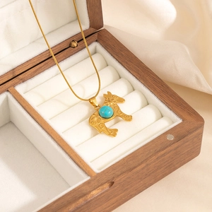 Macro view of gold horse pendant with blue turquoise stone on white velvet lining