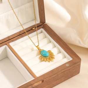 Golden necklace with turquoise gemstone pendant in a wooden jewelry box for a chic look