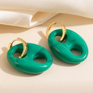Elegantes pendientes de resina verde con detalles de metal dorado sobre seda