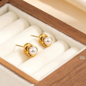 Lava design gold earrings with a round white pearl on luxury wood jewelry box display