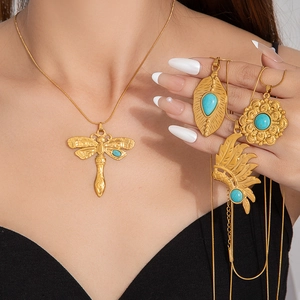 Detail of vintage gold flower and dragonfly pendants with turquoise stone on snake chain