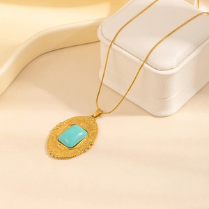 Detailed close-up of a vintage gold oval pendant necklace with a turquoise stone inlay