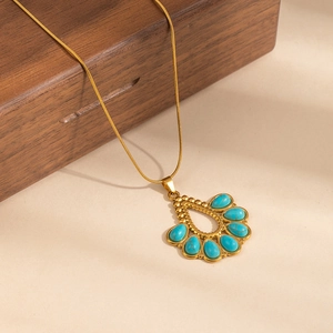 Detail of bohemian gold snake chain necklace with turquoise waterdrop pendant on wood