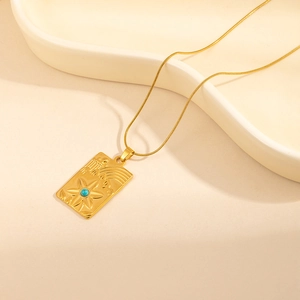 Detail of a vintage gold floral necklace with a blue bead on a wavy white tray
