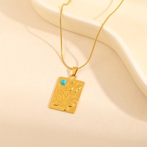 Detail of vintage gold rectangle pendant with embossed butterflies and blue stone inlay