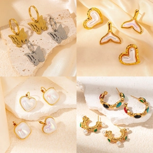 Detailed collection of gold plated wing and heart earrings on elegant fabric texture