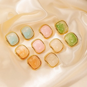 Detail of square gold-plated earrings featuring colorful marble resin on silk background