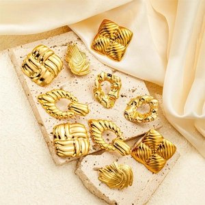Detail of vintage gold-plated wing earrings on stone base with soft silk background